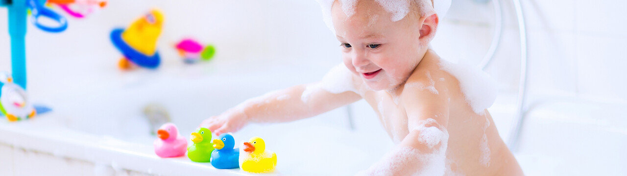 Niño bañándose en la bañera con patitos Niño bañándose en la bañera con patitos