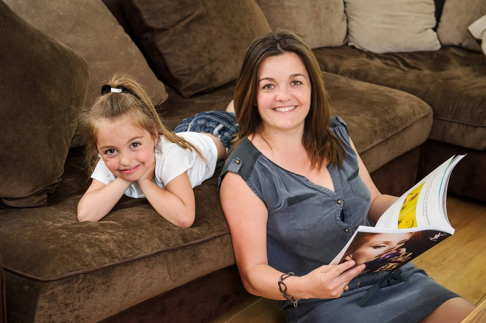 Mujer y niña en el sofa mirando una revista