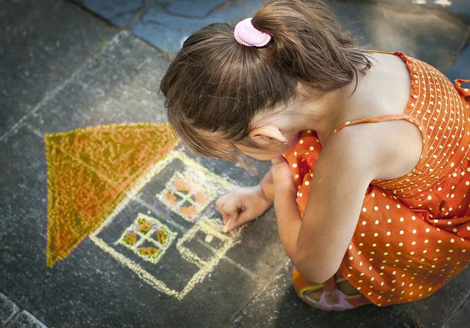 Niña pequeña pitando una casa en la acera