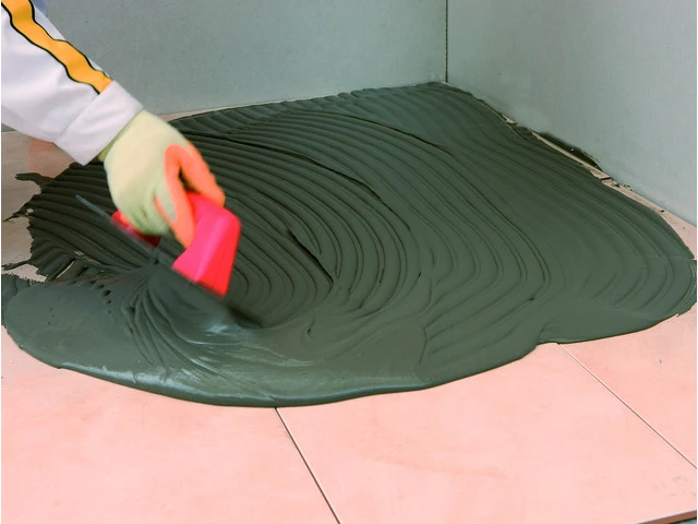 Aplicación del mortero cola sobre baldosa antigua en pavimento