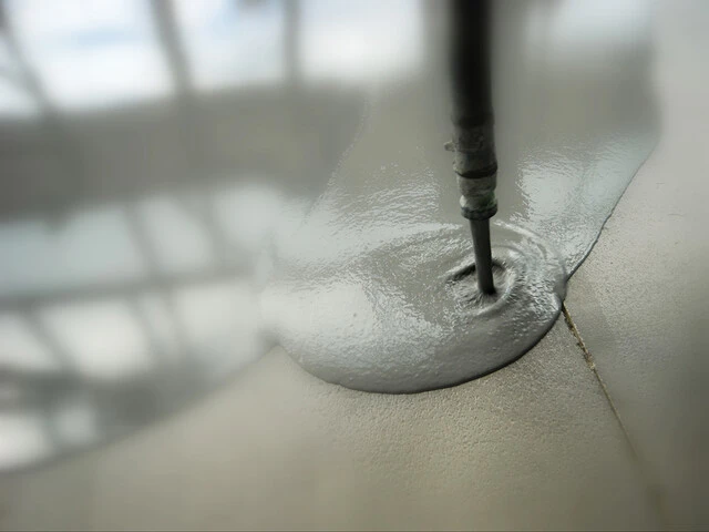 Mortero autonivelante cayendo por la boquilla de la manguera Mortero autonivelante cayendo por la boquilla de la manguera