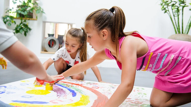 Niños pintando en el suelo sobre un papel