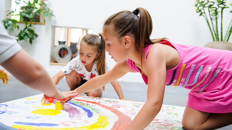 Niños pintando en el suelo sobre un papel Niños pintando en el suelo sobre un papel
