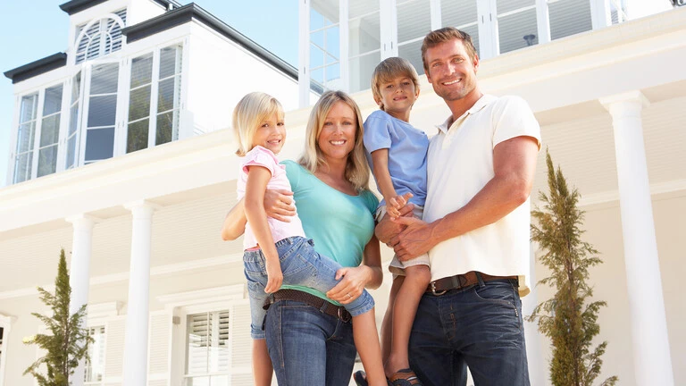 Familia en el exterior de su casa sonriendo