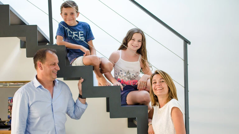Familia sentada en la escalera de casa sonriendo