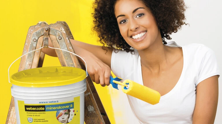 Mujer apoyada en escalera con brocha de pintura