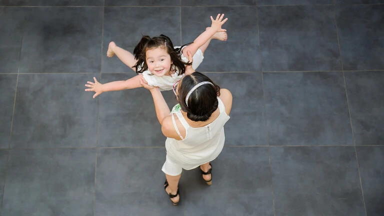 Mujer y niña jugando en el interior de la vivienda a dar vueltas