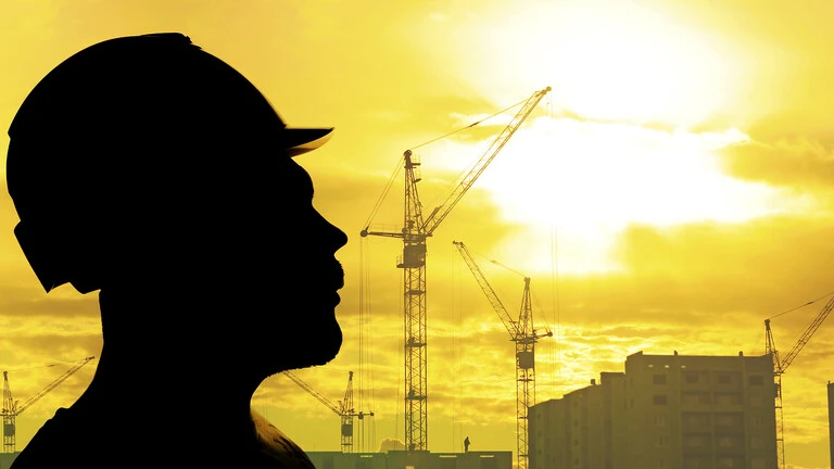 Silueta de un obrero detrás grúas